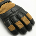 Pair of black leather ski gloves with tan suede accents and an adjustable buckle wrist strap on a white background.