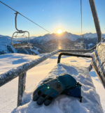 Pair of teal and grey ski gloves with leather knuckle patches and adjustable draw cord cuffs.
