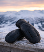 Black leather winter mittens with reinforced palm grip and pine background
