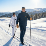 Tan leather winter mittens with reinforced palm grip and pine background